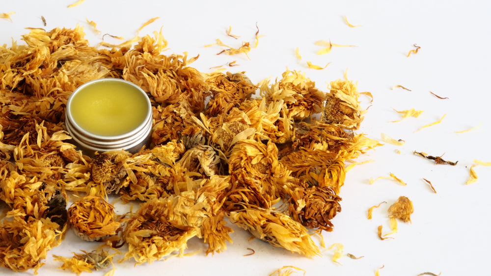 a pile of dried flowers next to a cup of oil